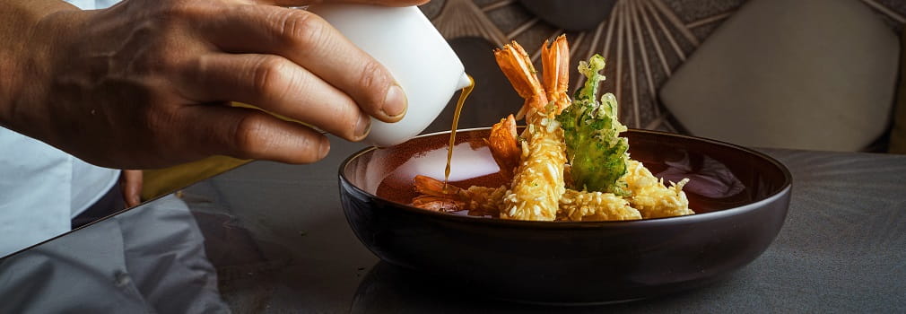 Chef pours sauce on fried shrimp
