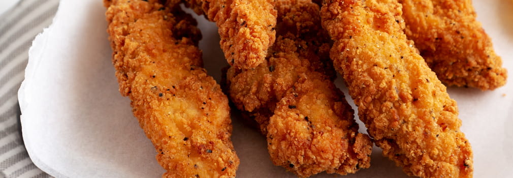 Chicken tenders with some spice on a decorative white napkin.